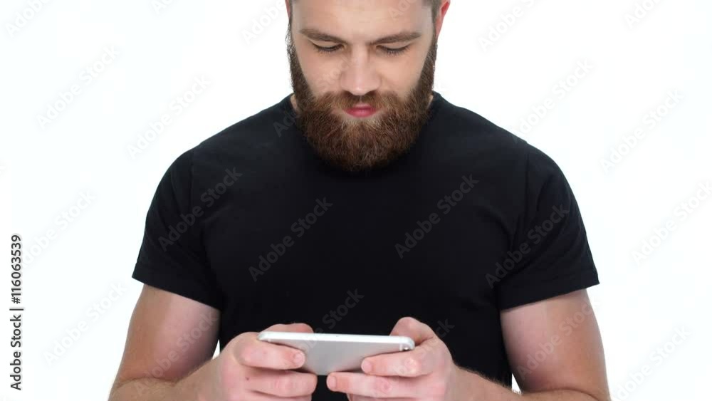 Poster Young cute smiling bearded man using smartphone 