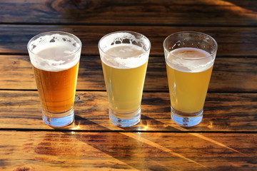 A selection of three draught beers on a wooden table