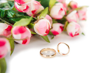 Wedding rings and flowers isolated on white background