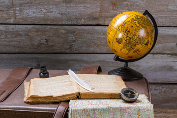 Feather on book beside inkwell. Globe and book on suitcase. The story of our adventures. The way was difficult.