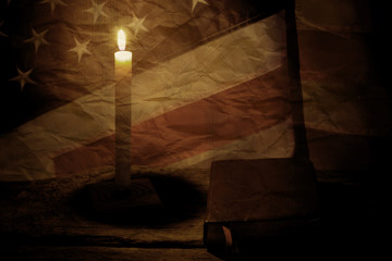 Old US flag and book. Closed book and burning candle. Power of knowledge is limitless. Past is a good teacher.