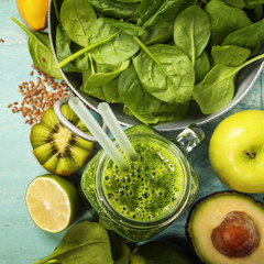Healthy green smoothie and ingredients on blue background