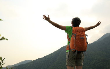 cheering young  woman hiker  enjoy the view on mountain peak cliff