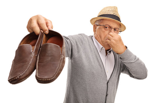 Disgusted senior holding stinky shoes