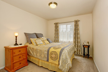 Lovely bedroom interior with yellow bedding, carpet floor and nightstand.