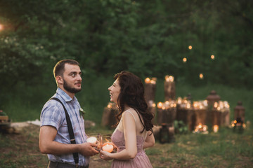 Romantic couple in love posing in the evening park decorated sparklers and candles