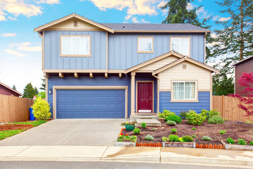 Fototapeta na wymiar Nice curb appeal of blue house with front garden and garage with driveway