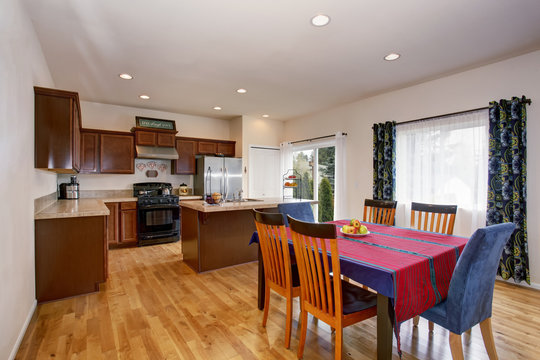 Bright kitchen and dining room interior with colorful curtains and hardwood floor.