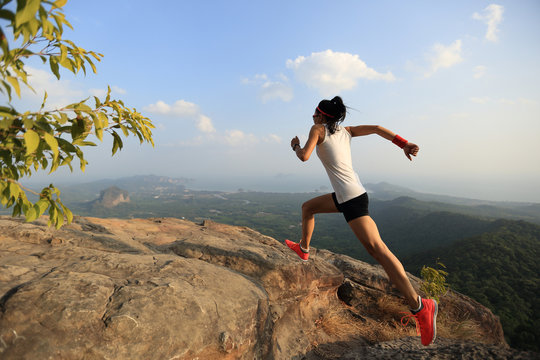young asian woman running on mountain peak cliff