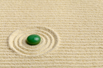 Artistic composition with green drop on surface of yellow sand