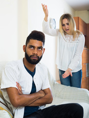 Blonde girl yelling at black boyfriend as quarreling indoors