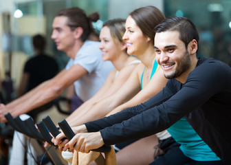 adults riding stationary bicycles in fitness club