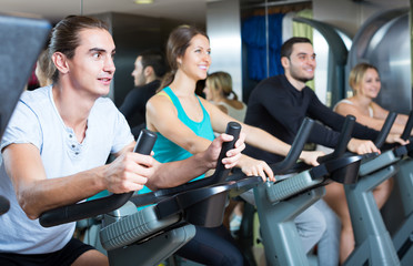 Fototapeta na wymiar Young adults on exercise bikes in gym.
