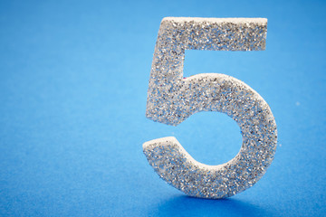 Number five silver color over a blue background. Anniversary