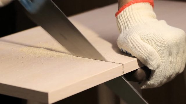 Man sawing wooden board with hand saw
