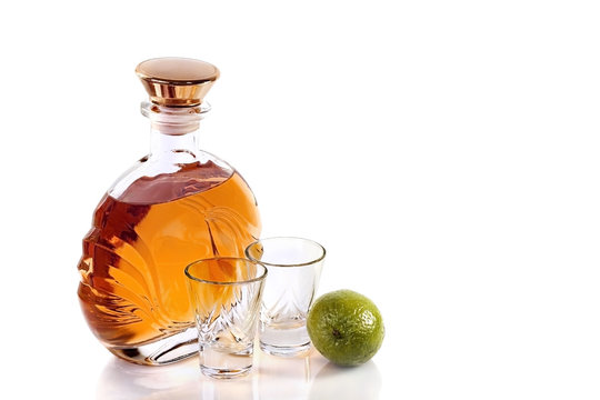 Bottle and shot glasses tequila with lime on white background