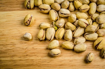 roasted and salted pistachios on wooden background.