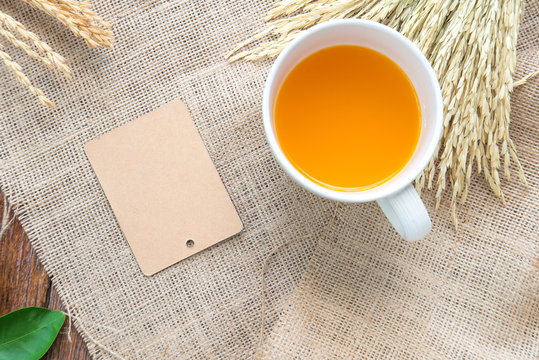Orange juice and brown paper label with rice drying on sackcloth