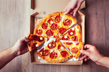 Close-up Of People Hands Taking Slices Of Pepperoni Pizza.
