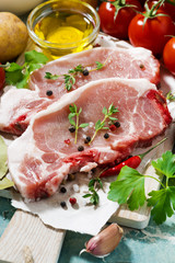 two pieces of pork on a cutting board and fresh foods, vertical