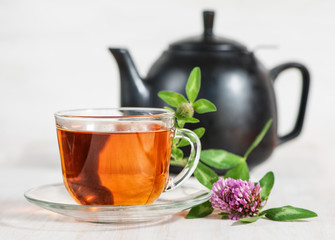 Cup of tea, teapot and branch of clover