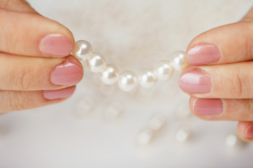 Female fingers hold thread with pearls