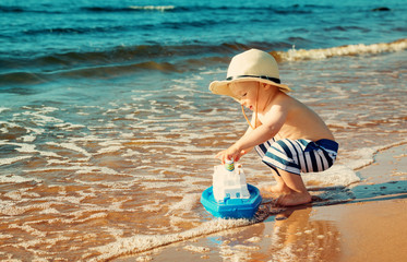 Baby boy playing with ship toy at sea