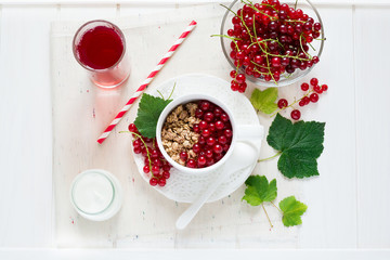 Healthy breakfast: muesli with yogurt and fresh berries in a bowl and juice on white wooden background