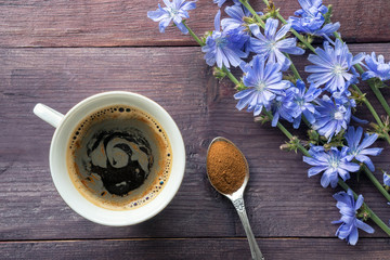 Chicory herbal drink and blue flowers on wooden table. Spoon with root powder. Top view