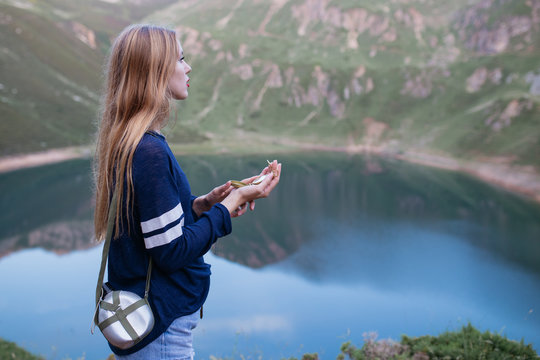 Young girl looking a compass with a canteen in her shoulder.