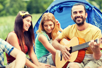 happy friends with drinks and guitar at camping