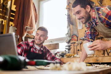two smiling carpenters with laptop at workshop