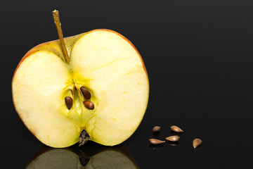 half of apple with some pips on dark background
