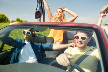 happy friends driving in cabriolet car