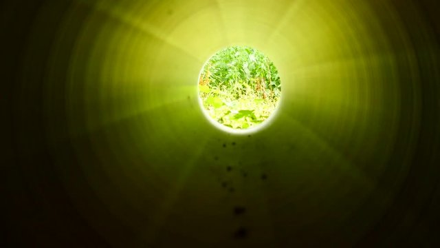 Movement inside of long plastic tube under ground. Strong green  light, structured ribbed wall of plastic pipe, green light at the circle end.