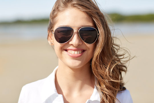 smiling young woman in sunglasses on beach