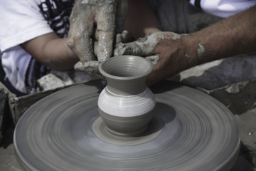 A men's hands guiding a child hands to help him to work with raw clay