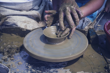 A men's hands guiding a child hands to help him to work with raw clay