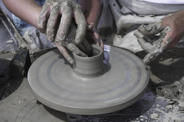 A men's hands guiding a child hands to help him to work with raw clay