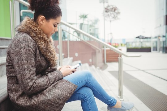 Woman using phone while sitting on steps