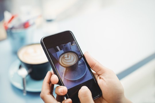 Hands holding mobile phone with photograph of coffee 