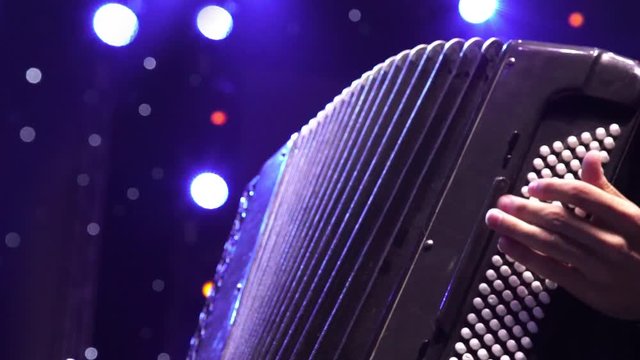 Musician hand playing accordion closeup in stage lights shadows