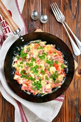 Scrambled eggs with ham, tomato and parsley