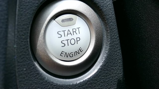 finger pressing start stop button in car automobile vehicle
