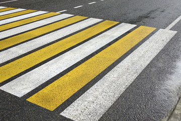 Fototapeta premium White Yellow Zebra Pedestrian Crossing On The Wet Asphalt Road
