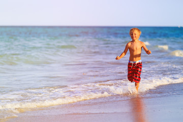 happy little boy running on sand beach