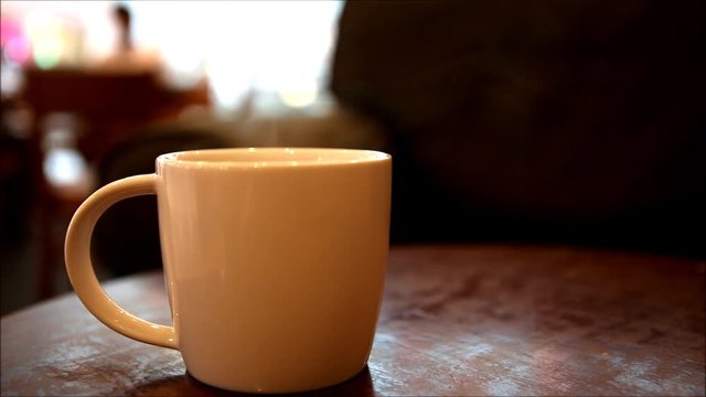 Cup of coffee with smoke on table at coffee shop