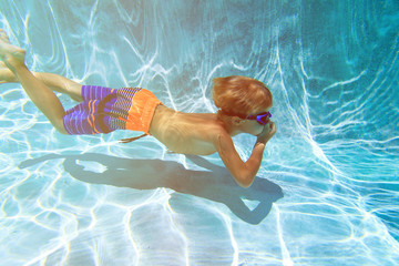 little boy swimming diving underwater