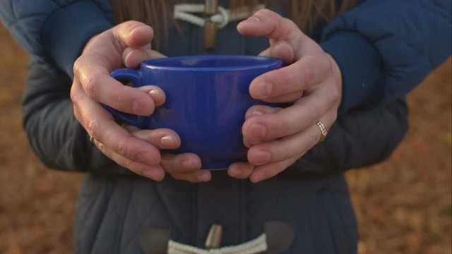 Hands spouses hold one large cup of tea.