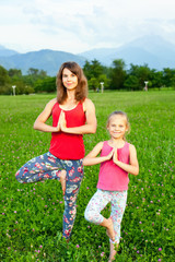 Mother and her daughter outdoors doing yoga